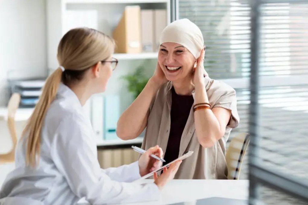 Paciente em tratamento do câncer sorrindo durante conversa com a profissional de saúde (imagem ilustrativa)
